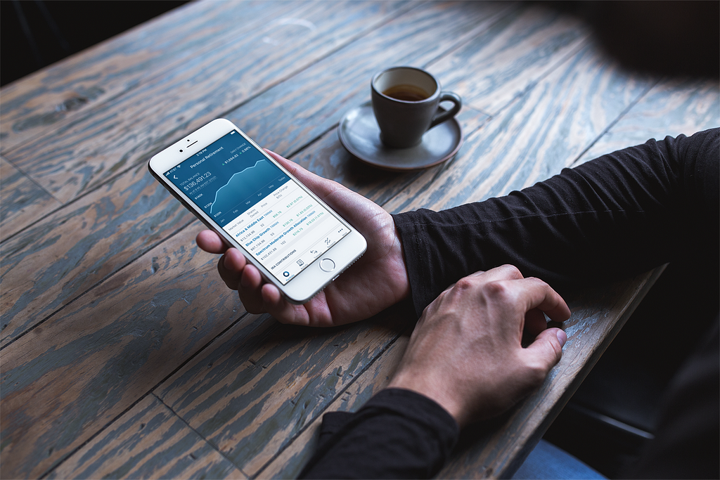 An image of someone using the T. Rowe Price mobile app on a phone in a coffee shop.