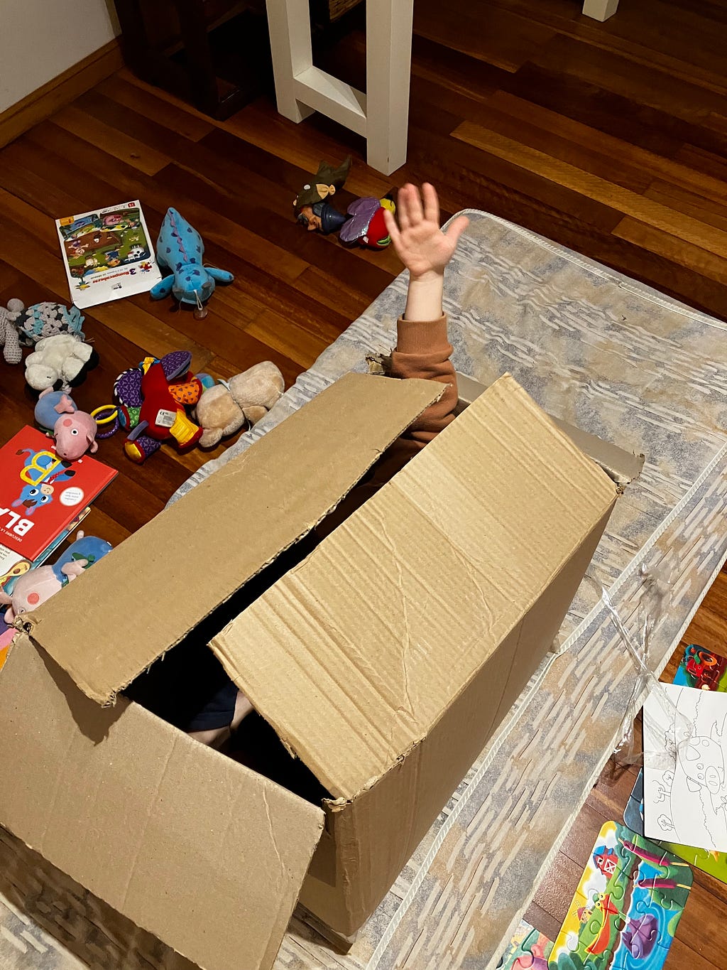 Kid in a box with his hand saying hi