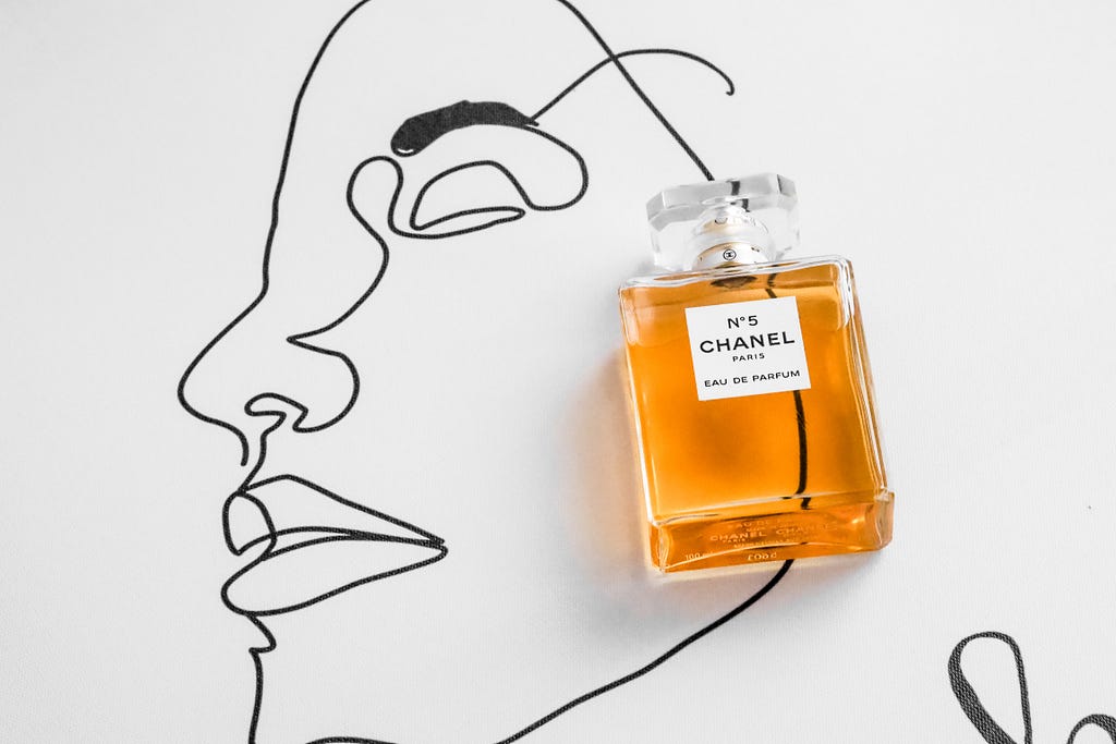 A bottle of Chanel №5 Eau De Parfum laying on top of a drawing of a face.