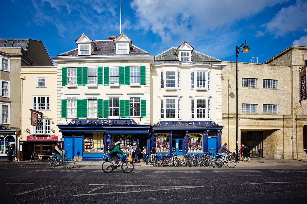 an exterior of a white stone multistory building with blue awnings on the ground floor advertising a book store