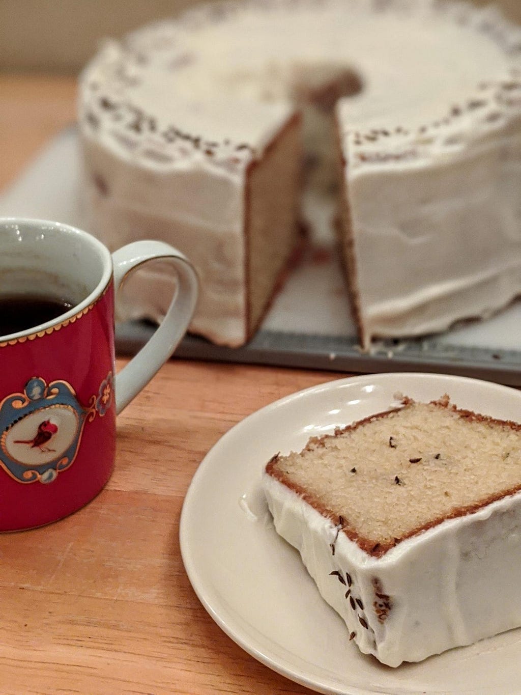 Irish caraway seed cake with a piece cut out on a plate, and cup of chai tea beside it.