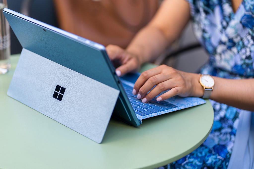 Image of someone using a Microsoft Surface blue laptop on a green table