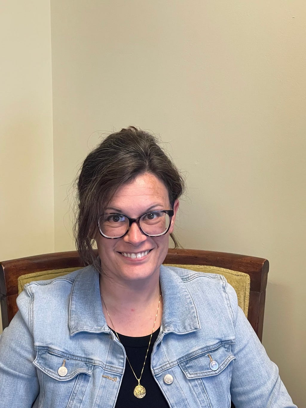 An individual sitting in a chair in their office looking at the camera and smiling.