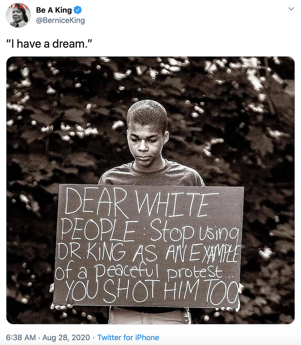 Young Black man holds a sign: “Dear White People: Stop using Dr. King as an example of peaceful protest…You Shot Him Too”