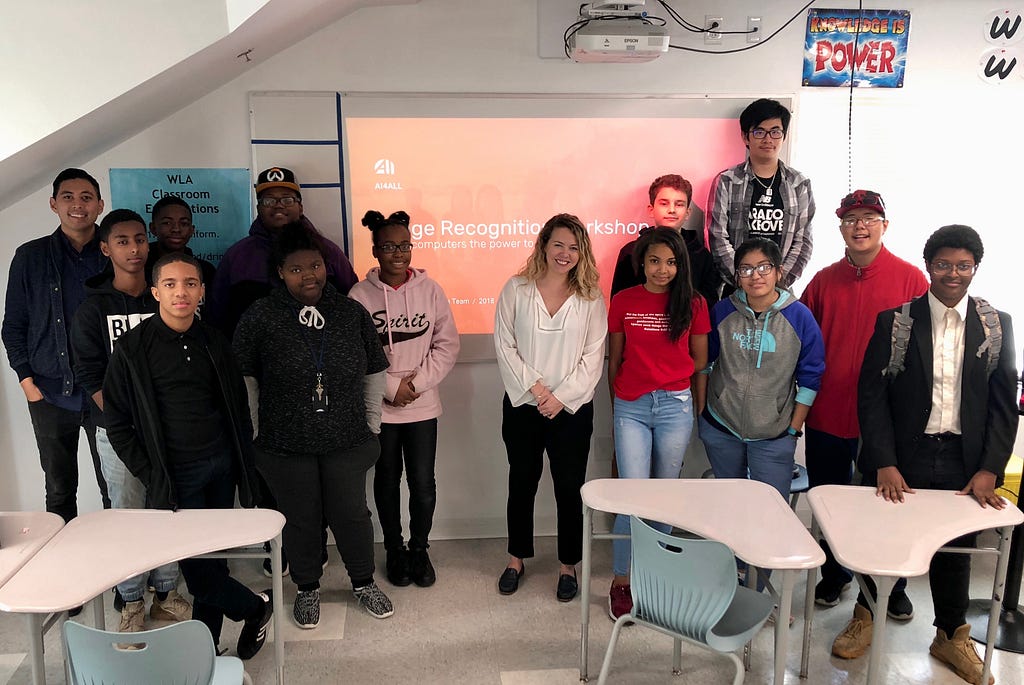 Group photo of twelve high school students, their computer science teacher, and a visiting artificial intelligence teacher in a classroom