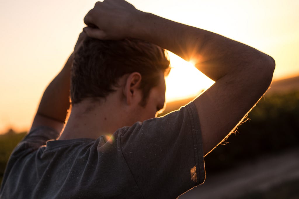 Pensive man outdoors with the sun setting.