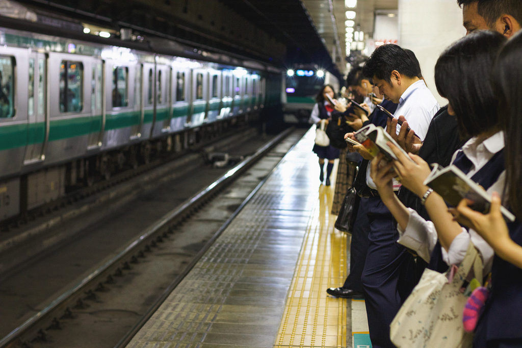 People waiting at the Japan subway, reading books.