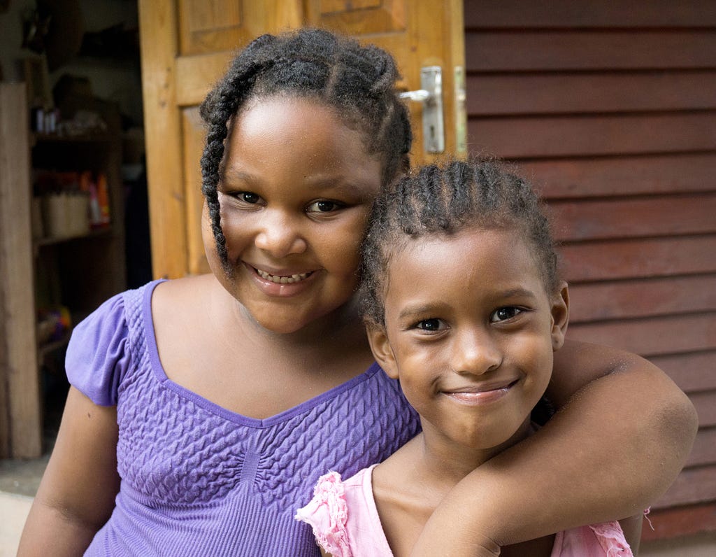 Two girls smile in the village of La Passe where ferries dock on La Digue Island in the Seychelles. © April Orcutt