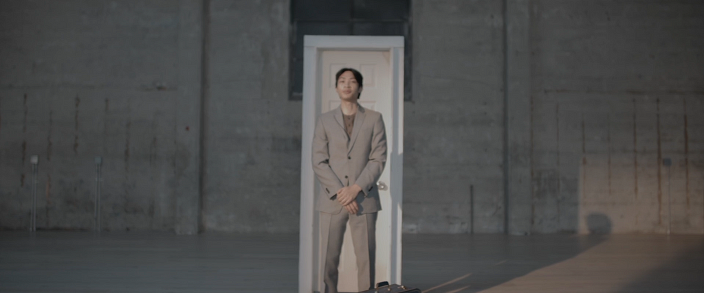 Narrator Rogelio Aranador stands before a white door in City Dance Live’s performance space.