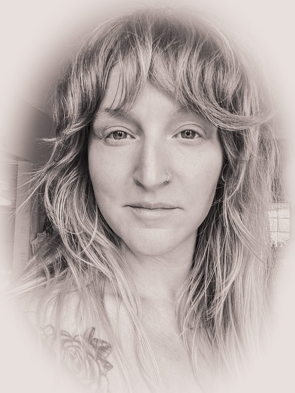 A black and white photograph of the author on date of publishing, hair wild and wispy, compassionate confidence radiating for her eyes