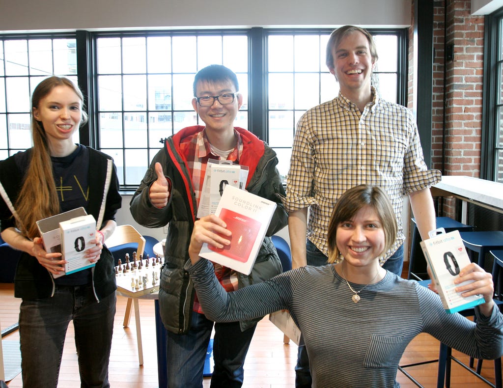 Two women and two men posing with boxes of prizes and smiling.