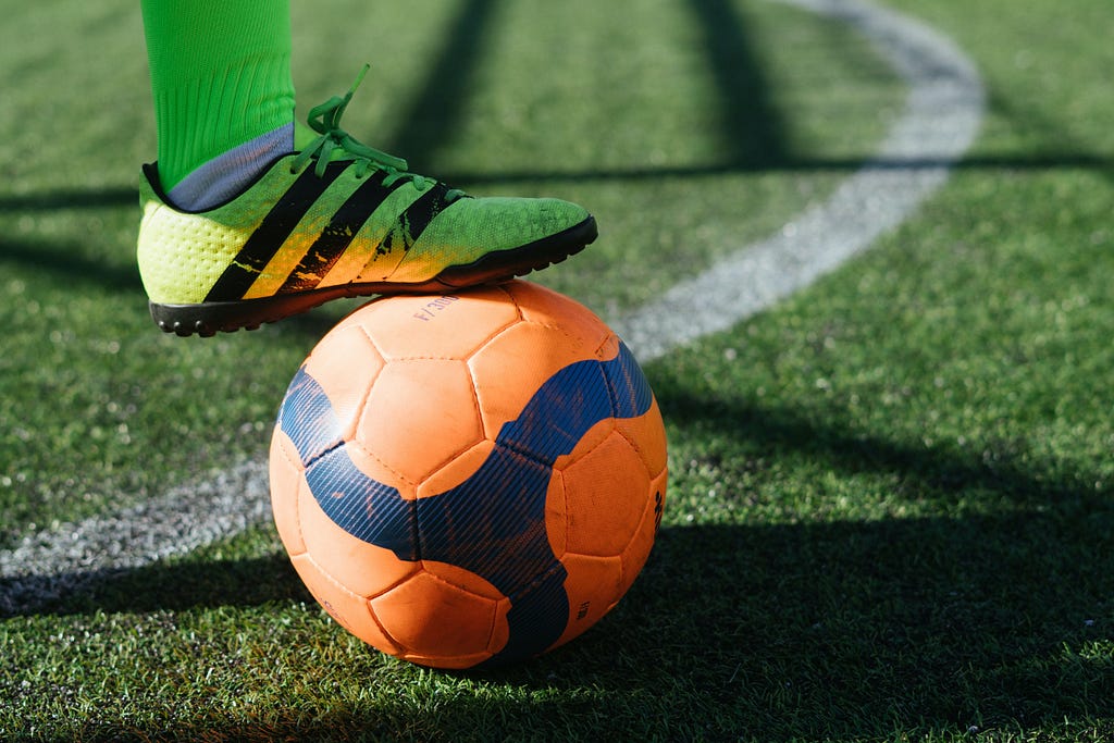 a foot on top of a soccer ball to represent a sporty brand image