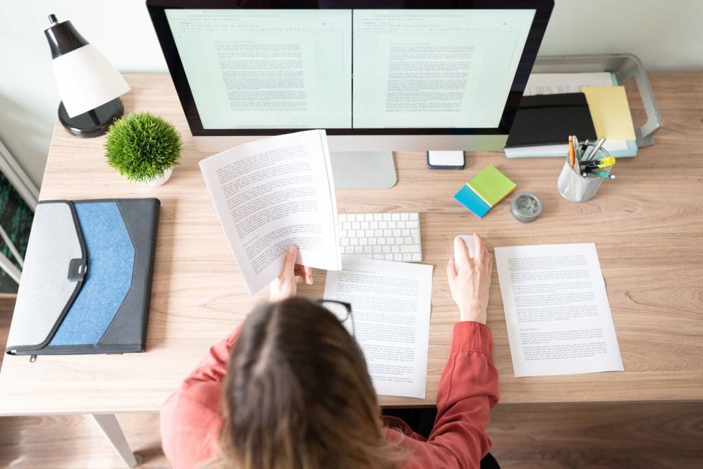 Top view of the workspace and office of a female translator working on a document and checking some references.