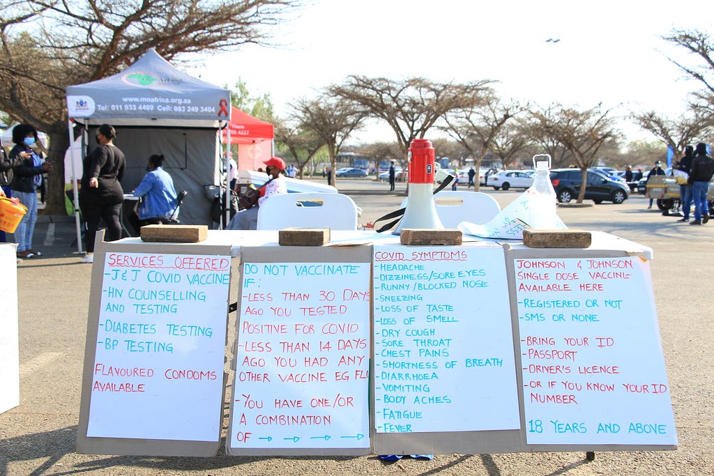 Four signs outside a community health event indicate the medical services offered on site.