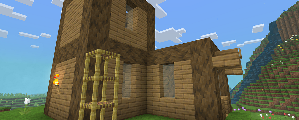 A handmade wooden Minecraft shack with scaffolding and torchlight, set against a mountain and flower field.