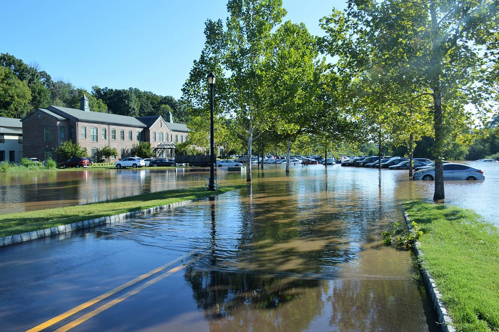 a flooded street leads to a flooded apartment building and parking lot