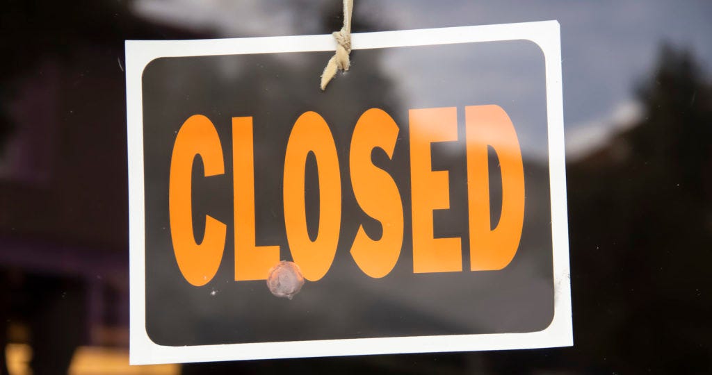 Closed sign hanging in business window by a string
