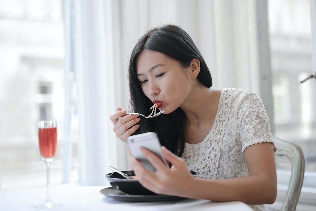 Asian young female eating noodles at cafe