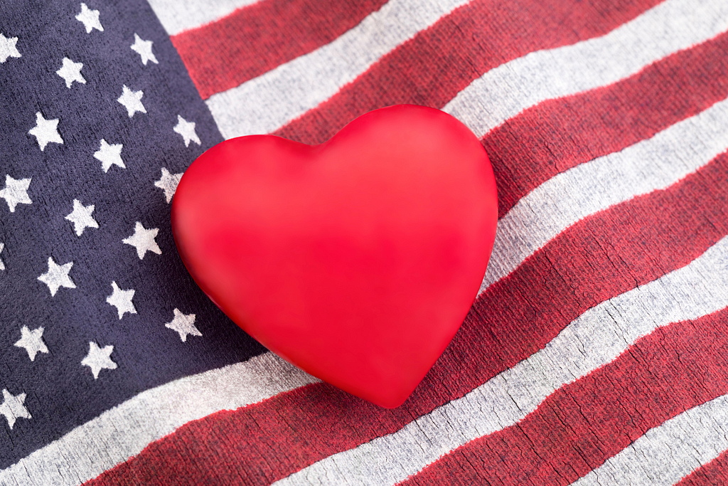 Red heart shaped object resting on an American flag