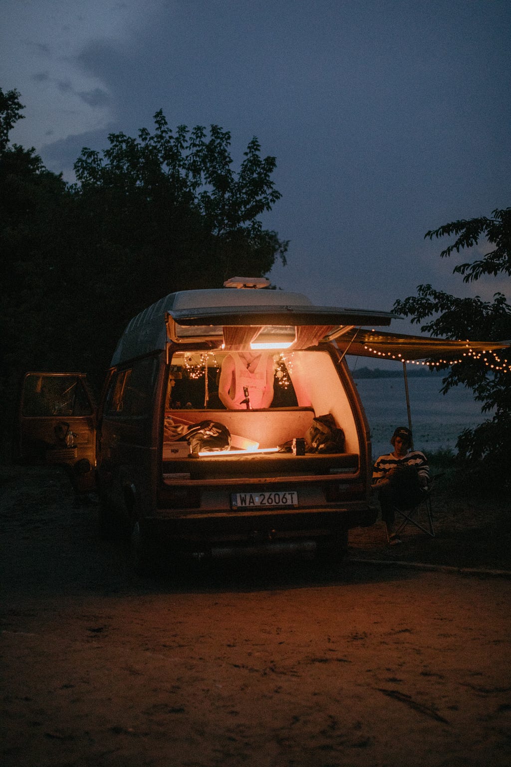 Vintage microcamper at night with backdoor open and fairy lights