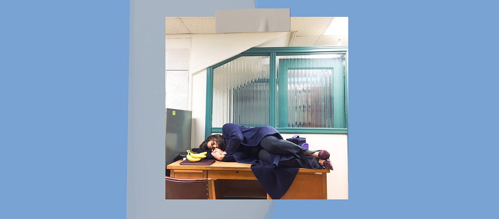 a picture of Diana Leite, the author of this article, sleeping on top of a desk in a university office.