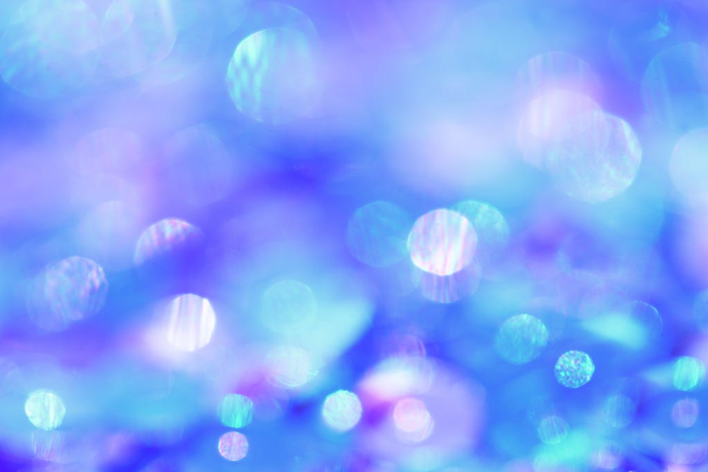 A blue and lilac background with dots of iridescent light creating a dreamlike state.