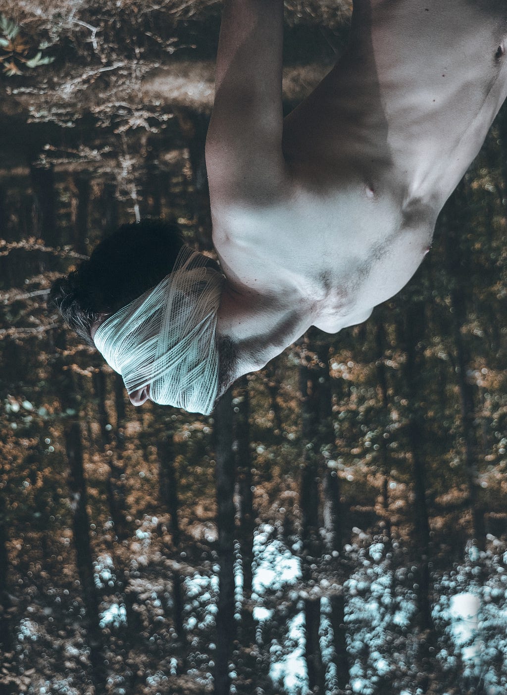 An upside down photo of a shirtless man who is bound and gagged