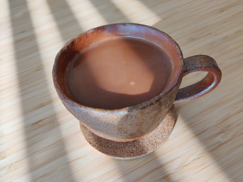 A handmade ceramic cup holding chocolate.