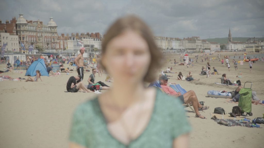 The author stands in front of the camera at the beach however instead of the background being blurred, the author is.