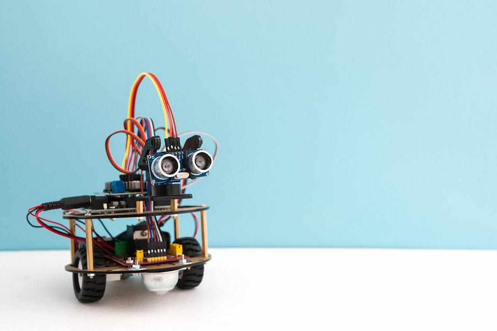 A small robot with wheels, cameras, and a built-in power source is powered by an Arduino board.