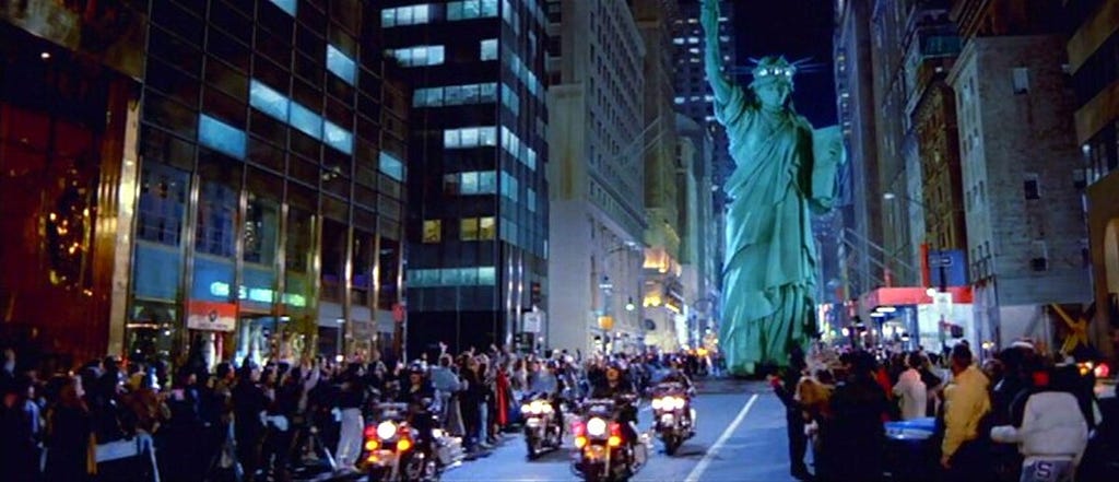A still from Ghostbusters II showing the characters “driving” the Statue of Liberty down a street in Manhattan.