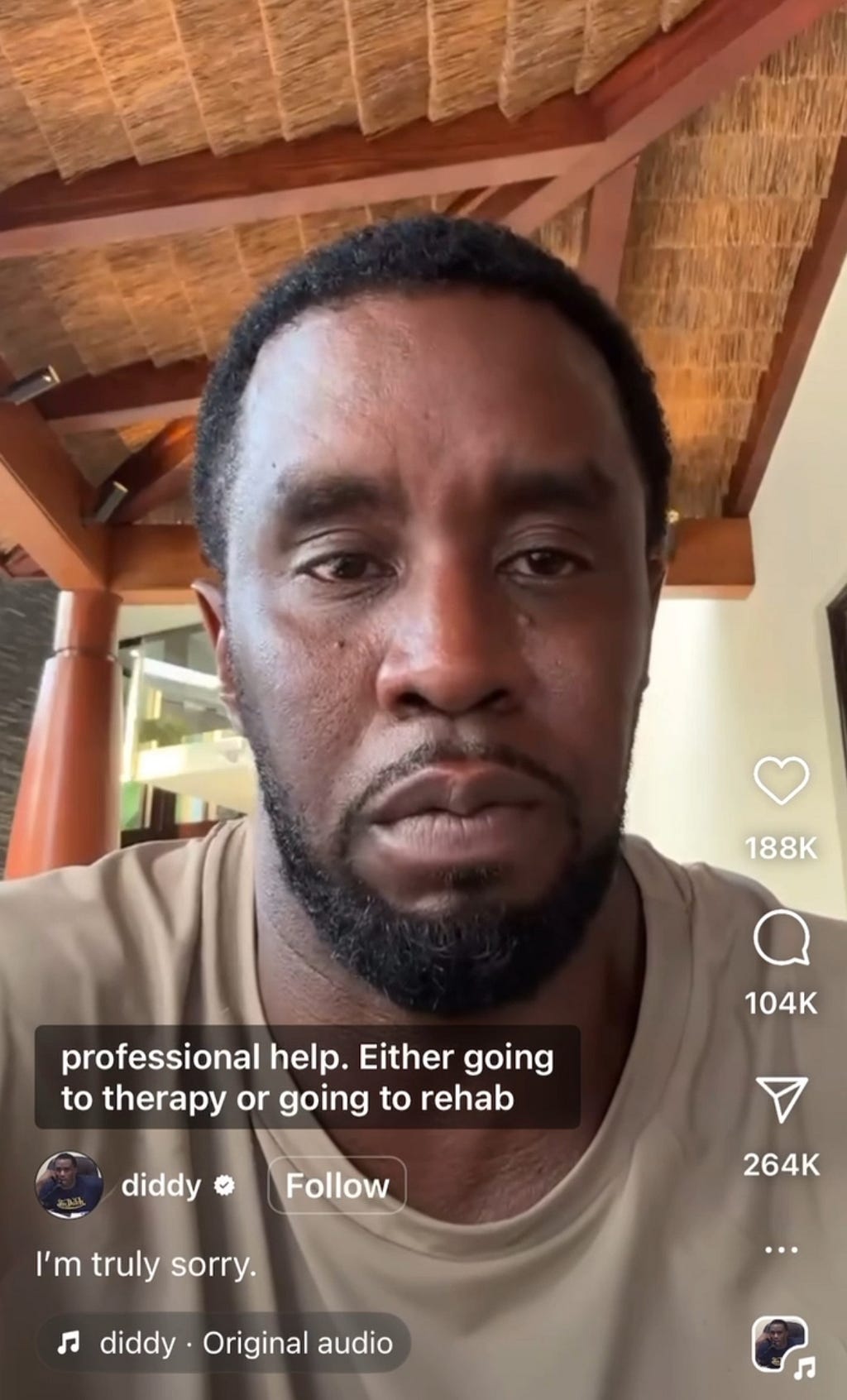A screenshot of Diddy’s fake “apology” video posted on his instagram. He has an unsmiling face, is wearing a tan t-shirt, and is sitting under a thatched roof in some swanky place. The caption reads, “I’m truly sorry,” but he accidentally left off “for being caught.” The closed captioning that appears reads, “professional help. Either going to therapy or going to rehab.” There are 188K likes (who *are* these people?), 104K comments (many of which are not abuse informed), and 264K shares.
