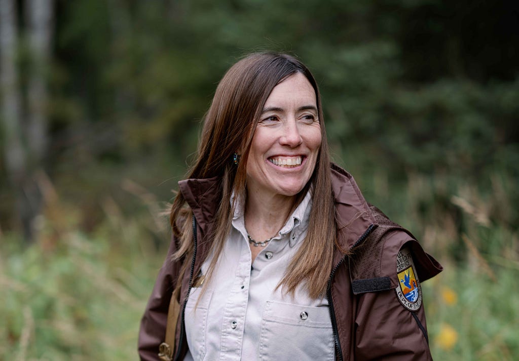 woman in a USFWS uniform in the woods