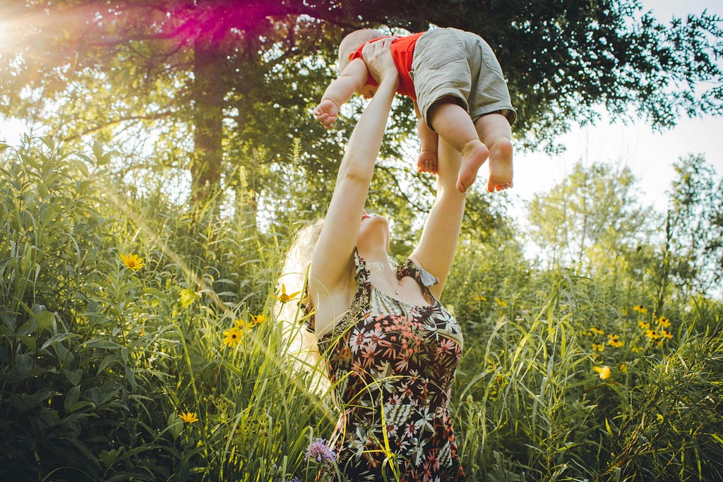 A mother holding her child and playing in a garden