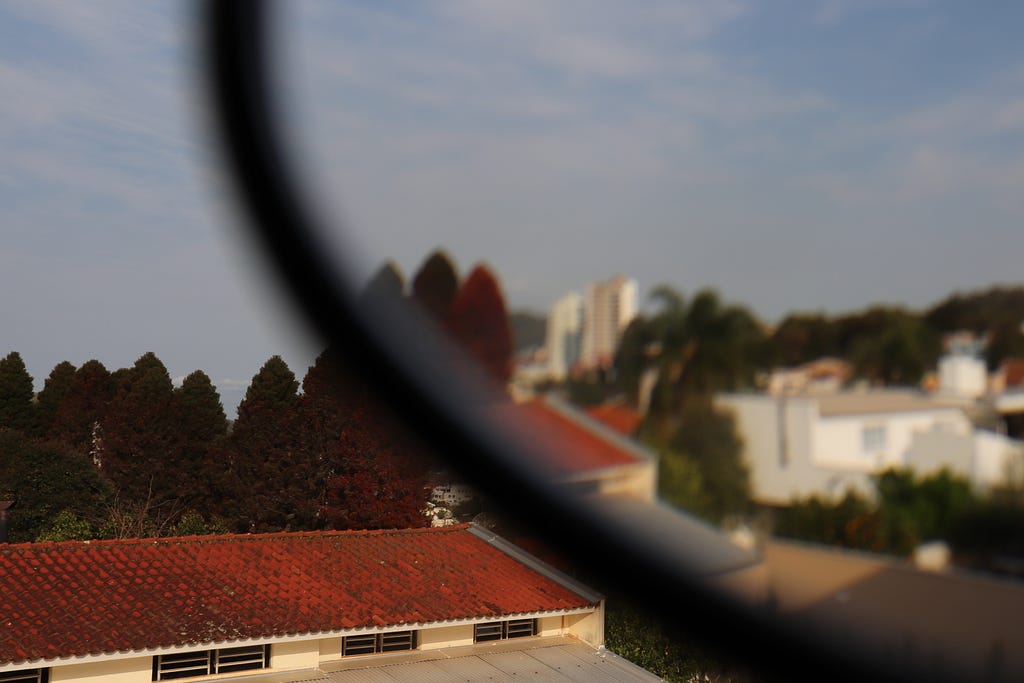 paisagem com casas e árvores distorcida e desfocada em partes por uma lente de óculos