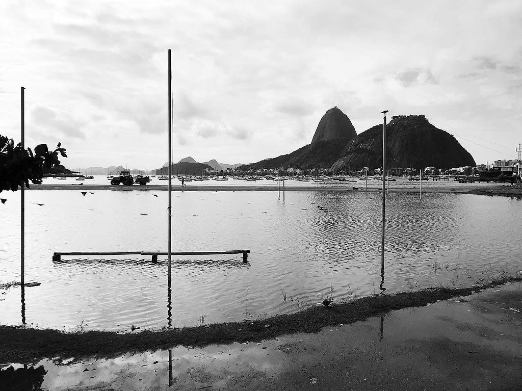 Uma foto em preto e branco que mostra o Pão de Açúcar e a baía de Guanabara com muitos barcos no fundo,