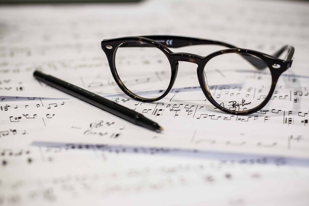 Stock photo of eyeglasses and a pen on top of sheet music, by Dayne Topkin on Unsplash