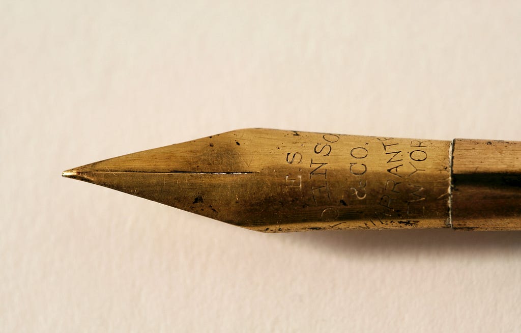 A close-up photo of the tip of a golden pen.