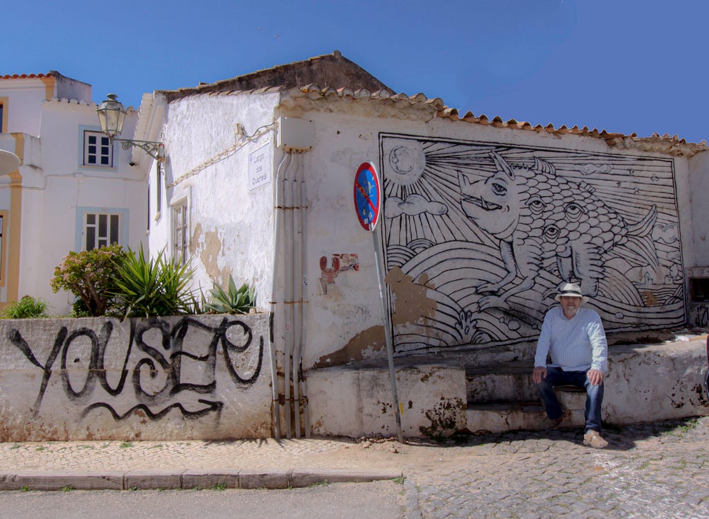 a man sitting by a wall painting