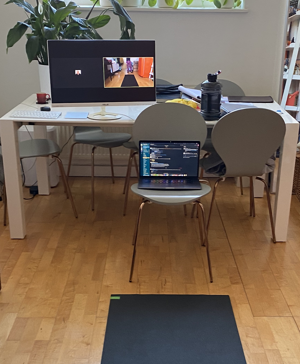 A yoga mat is unrolled on the floor, in front of a forward-facing chair with a laptop on top of it.