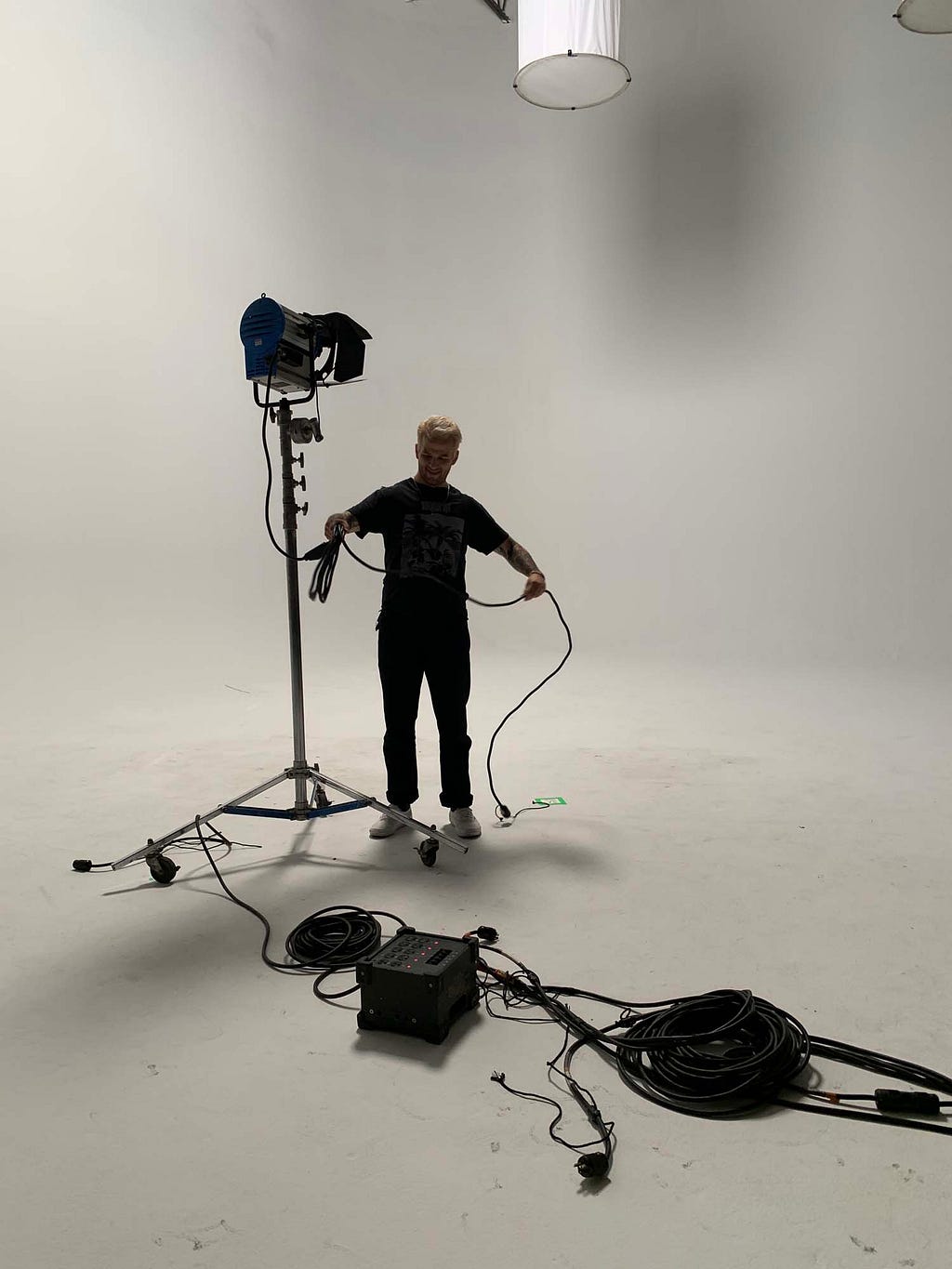 Photographer’s assistant setting up photo lights in a white studio