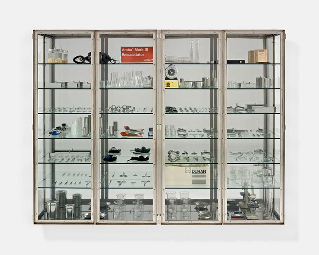 A large metal and glass cabinet filled with various stainless steel medical instreuments and glass containers.