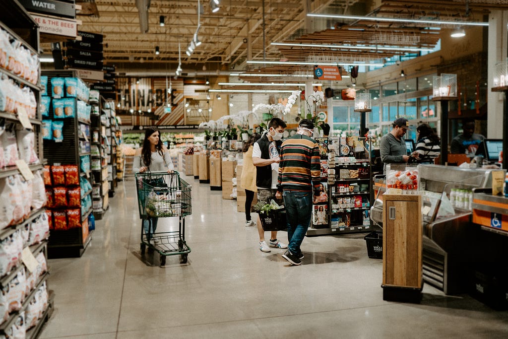 A women walking with a grocery cart in whole foods.