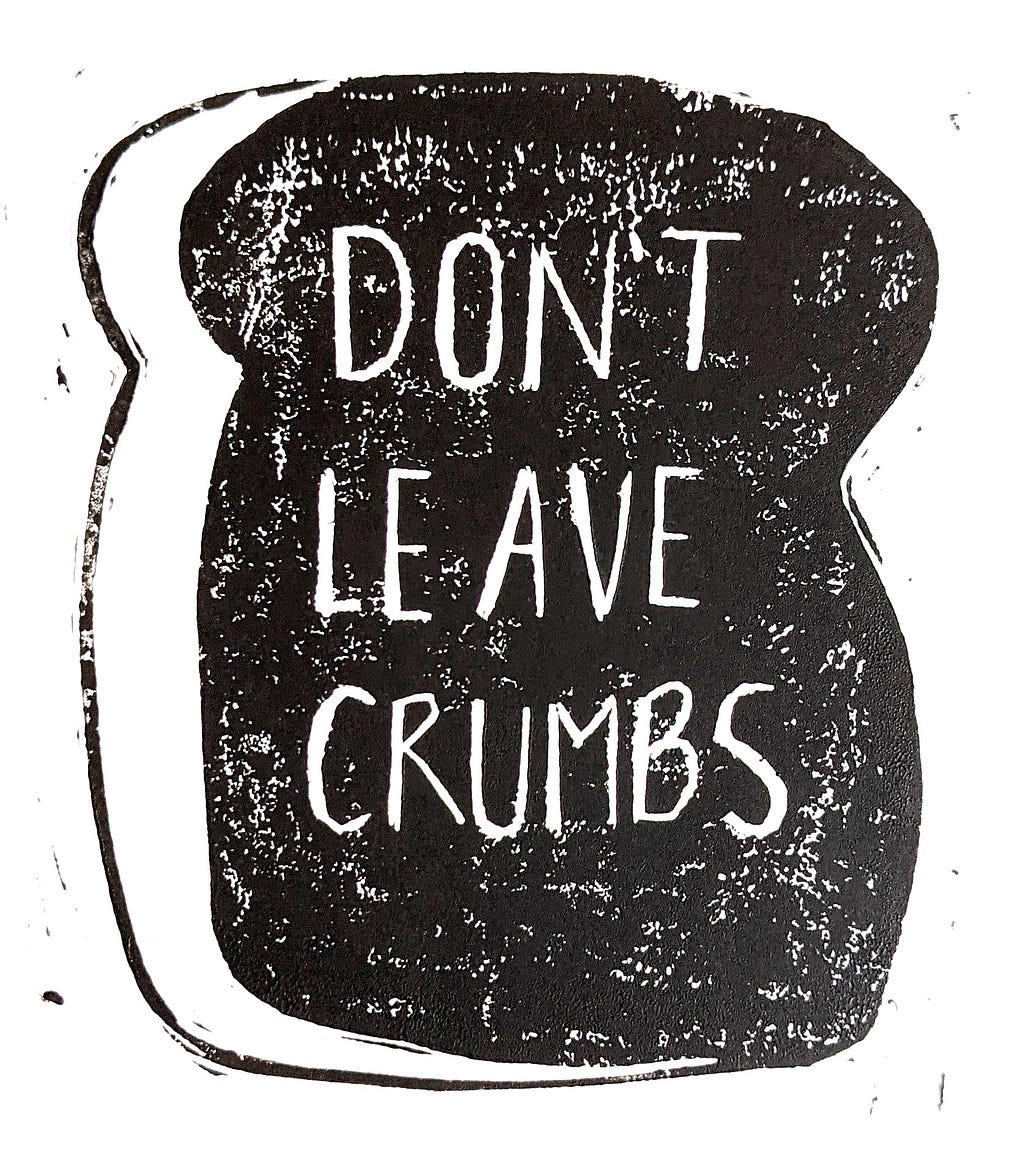 A lino-cut print of a piece of bread with “don’t leave crumbs” written in the middle.