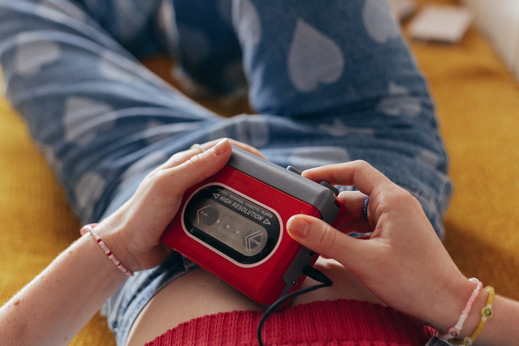 a woman in heart-print jeans and a red crop top, holding a cassette player and embodying the Y2K style