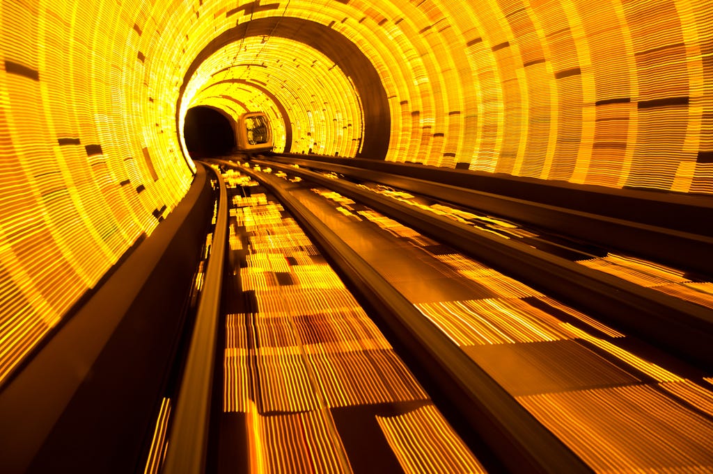 A photo of a golden tunnel with a transportation vehicle moving along the rails