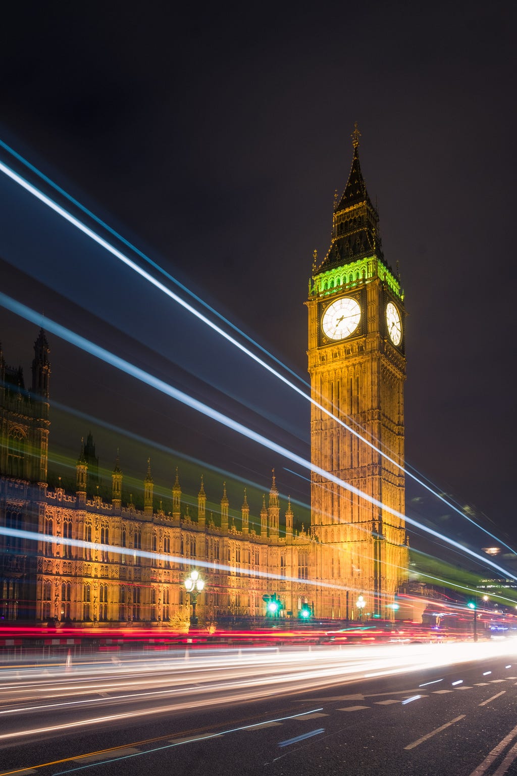 A stylized long exposure photo of the tower and clock Big Ben at night, with streaks of light suggesting movement. Photo by Christian Holzinger on Unsplash.