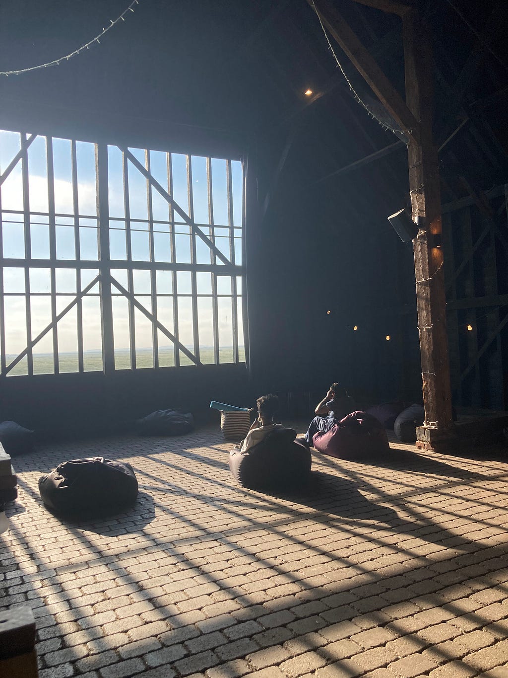 Light streaming into the dark barn in the morning while guests and Black Design Guild ream sit on beanbags for the meditation loop.