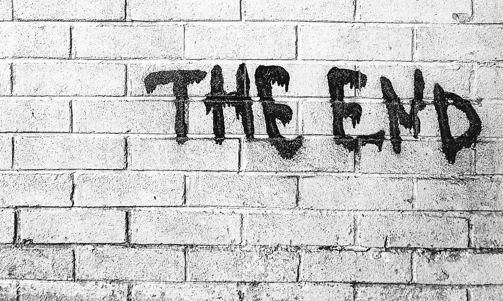“The end” in black graffiti against white brick