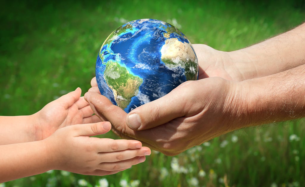 Adult hands handing over miniature globe to hands of child.